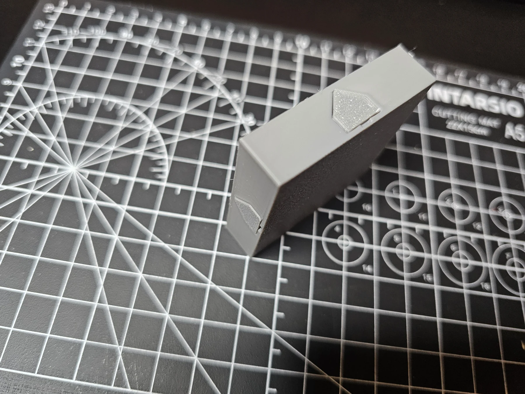 Side profile of a printed dungeon floor tile with a crest on the side.