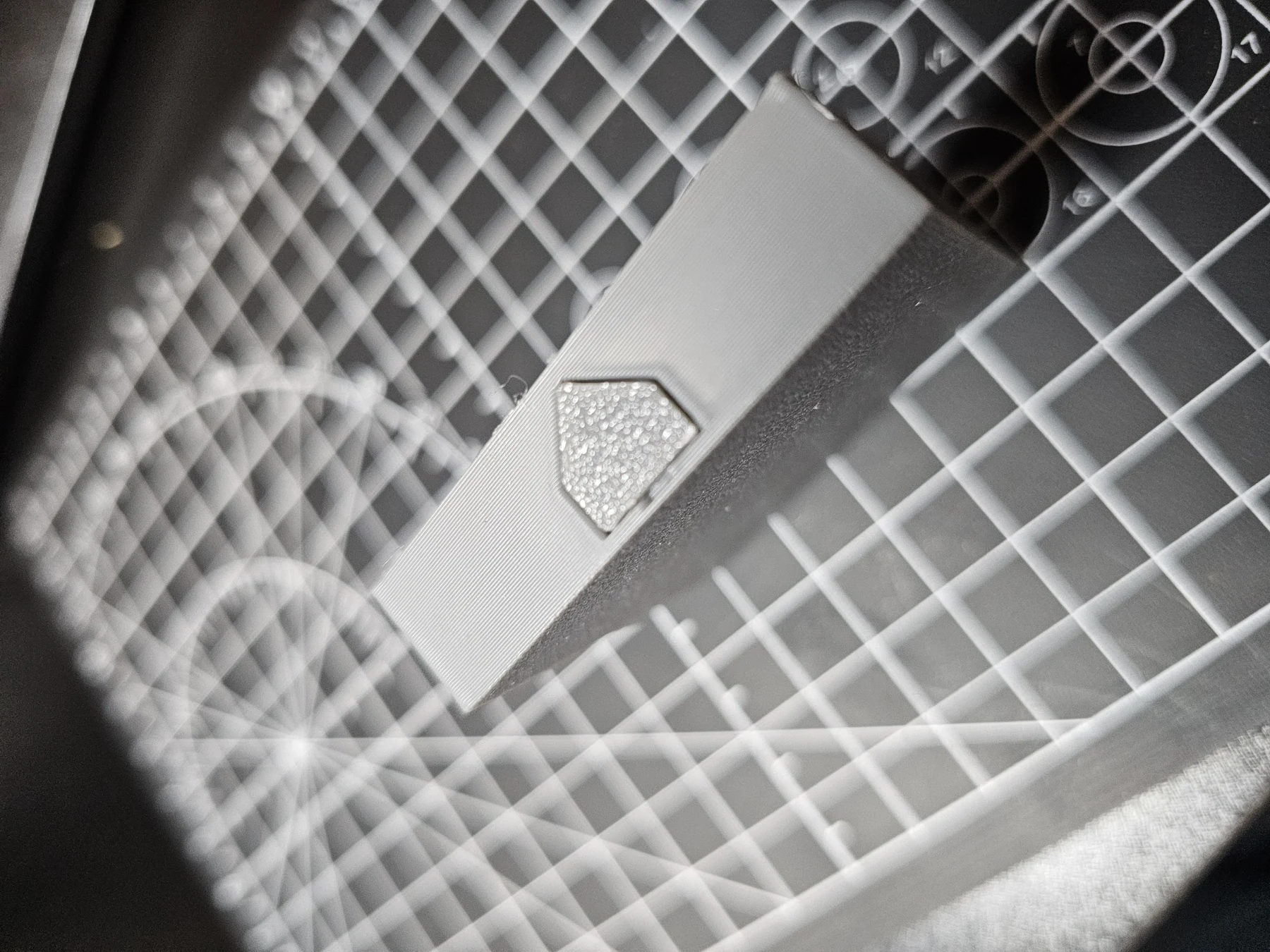 Close-up of the underside or side access area of a floor tile on a cutting mat.