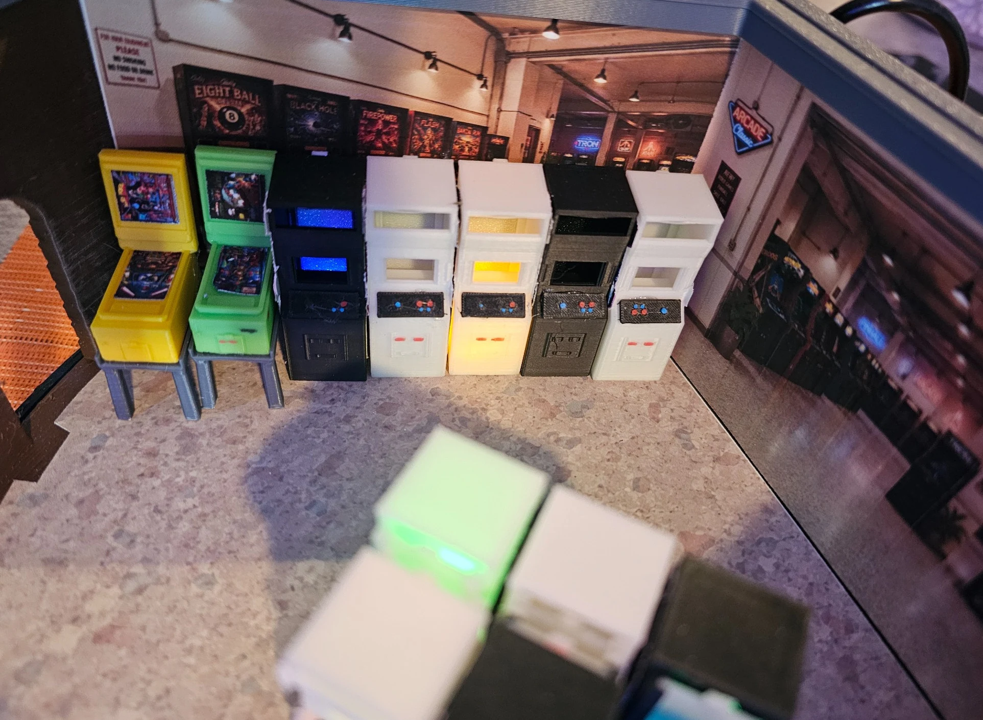 Photograph of a row of printed arcade cabinets installed in the miniature arcade